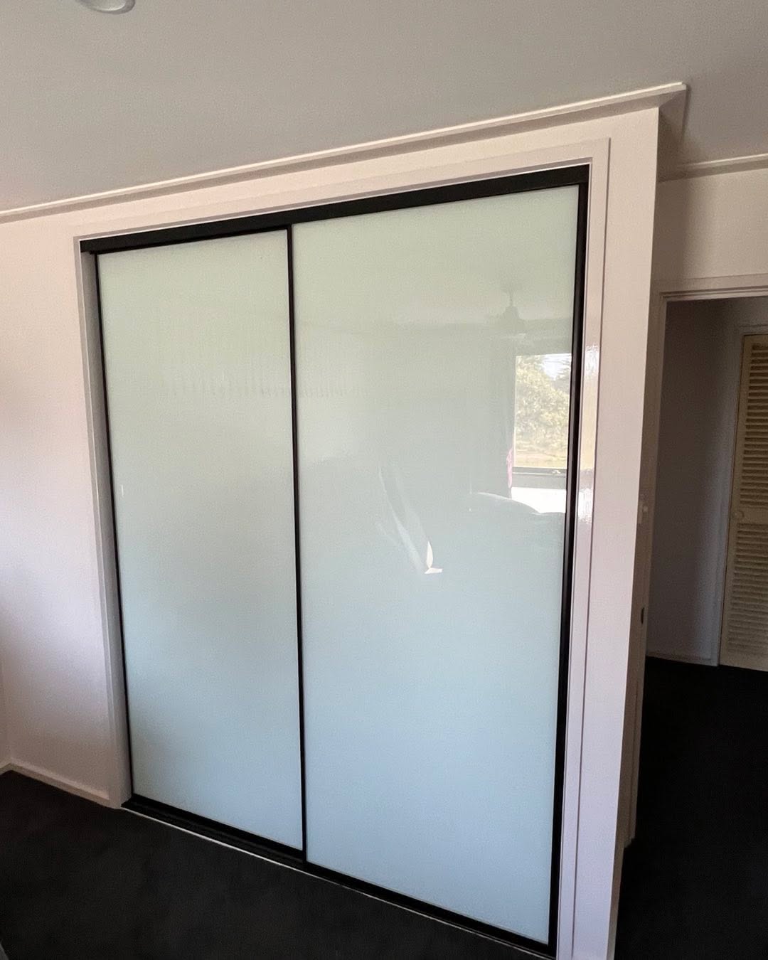Bedroom with white-framed sliding wardrobe doors